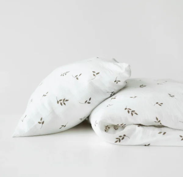 Vauvan pussilakanasetti. Valkoinen pohja, jossa tummemmalla lehti kuviointia.